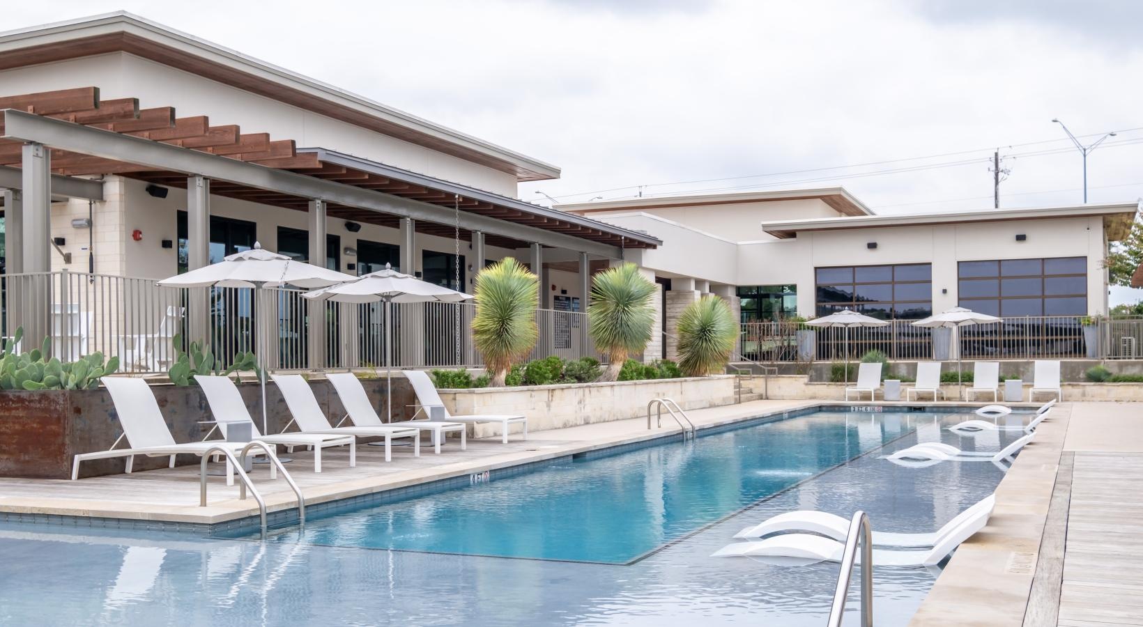 Settle into comfort at Berkshire Santal a swimming pool with chairs and umbrellas next to it