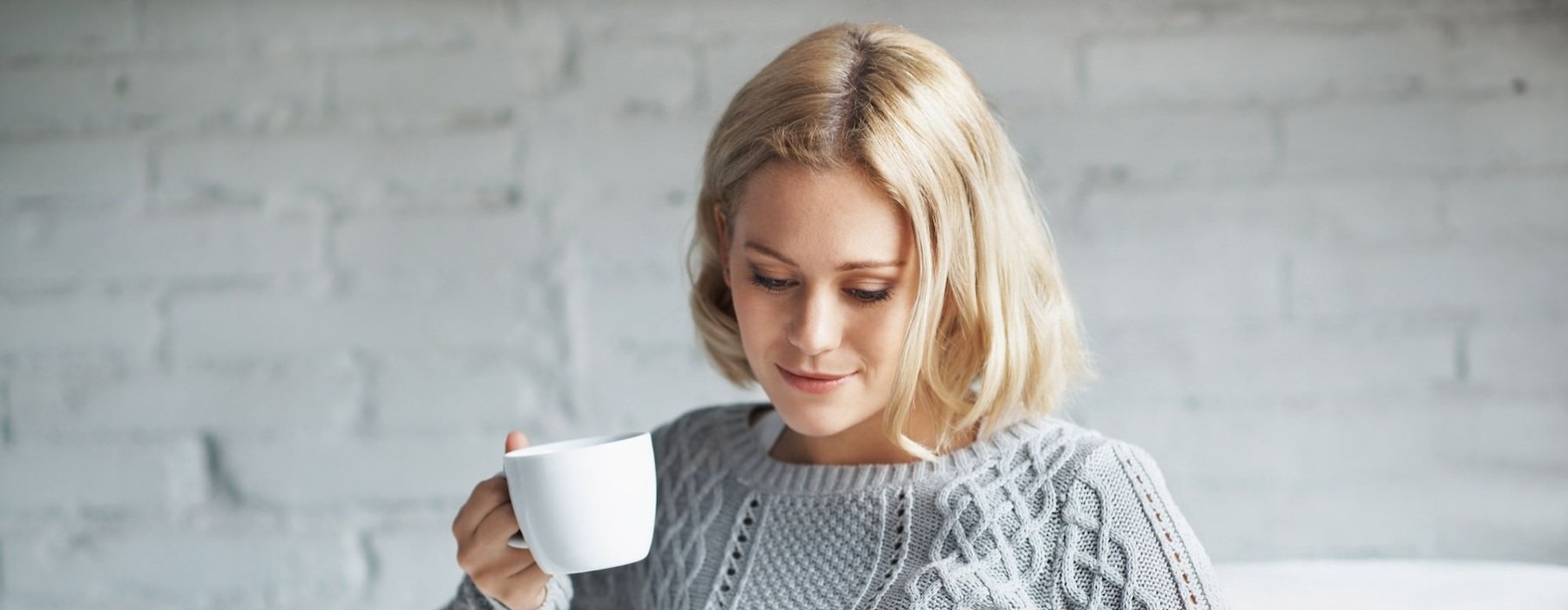 a person sitting down holding a cup looking at a tablet